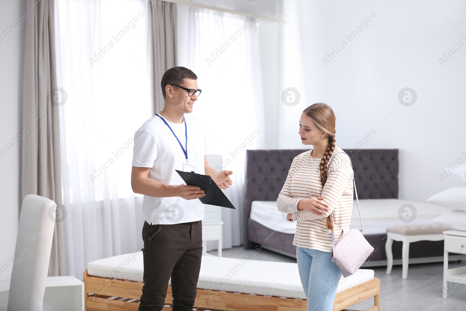 Photo of Salesman consulting young woman in mattress store