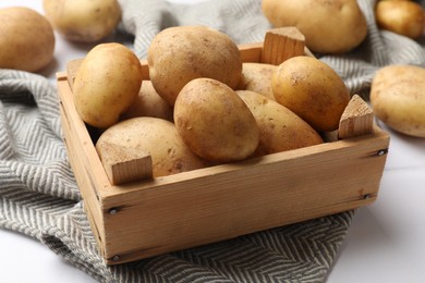 Photo of Raw fresh potatoes and wooden crate on white tiled table