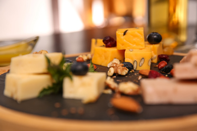 Photo of Different types of delicious cheeses, berries and nuts on board, closeup