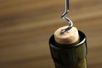 Photo of Opening wine bottle with corkscrew on color background, closeup. Space for text