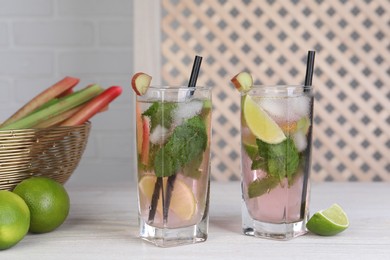 Tasty rhubarb cocktail with lime on white wooden table indoors