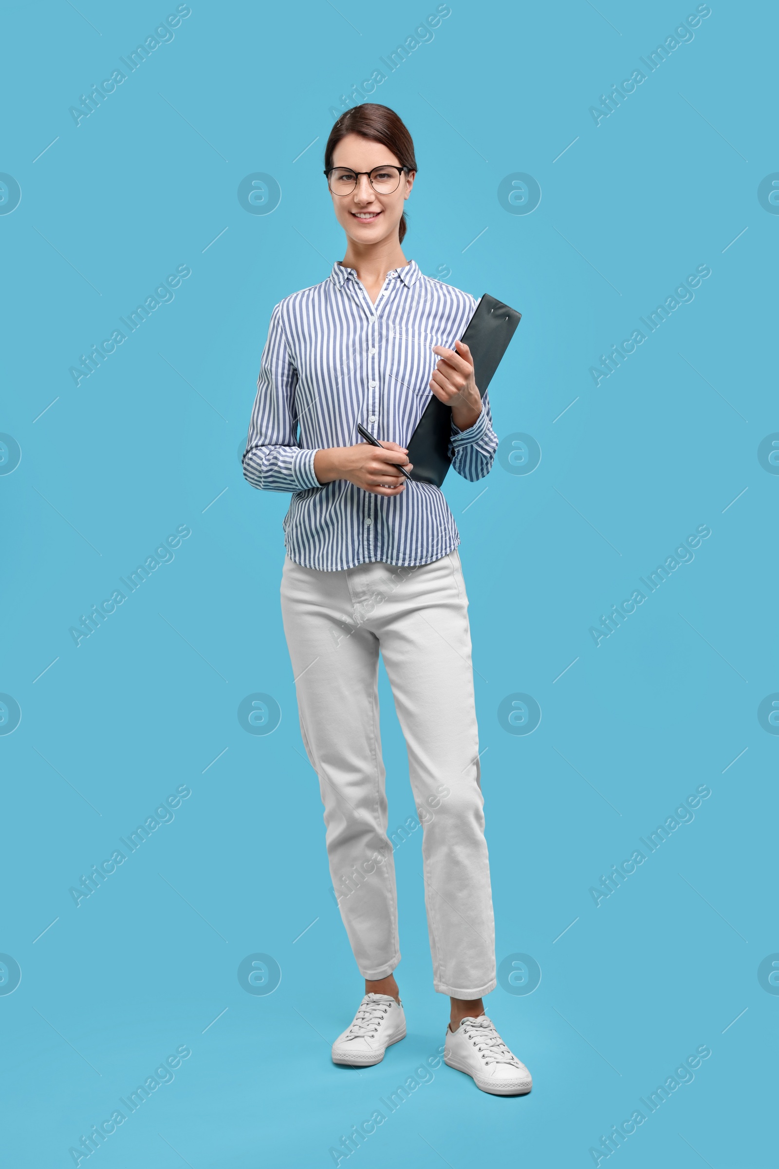 Photo of Happy secretary with clipboard and pen on light blue background