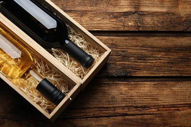 Boxes with bottles of wine on wooden background, flat lay. Space for text