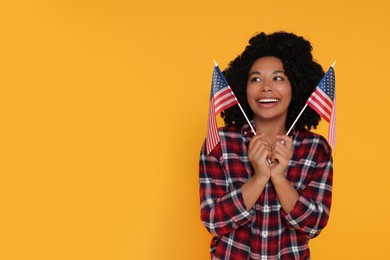Photo of 4th of July - Independence Day of USA. Happy woman with American flags on yellow background, space for text