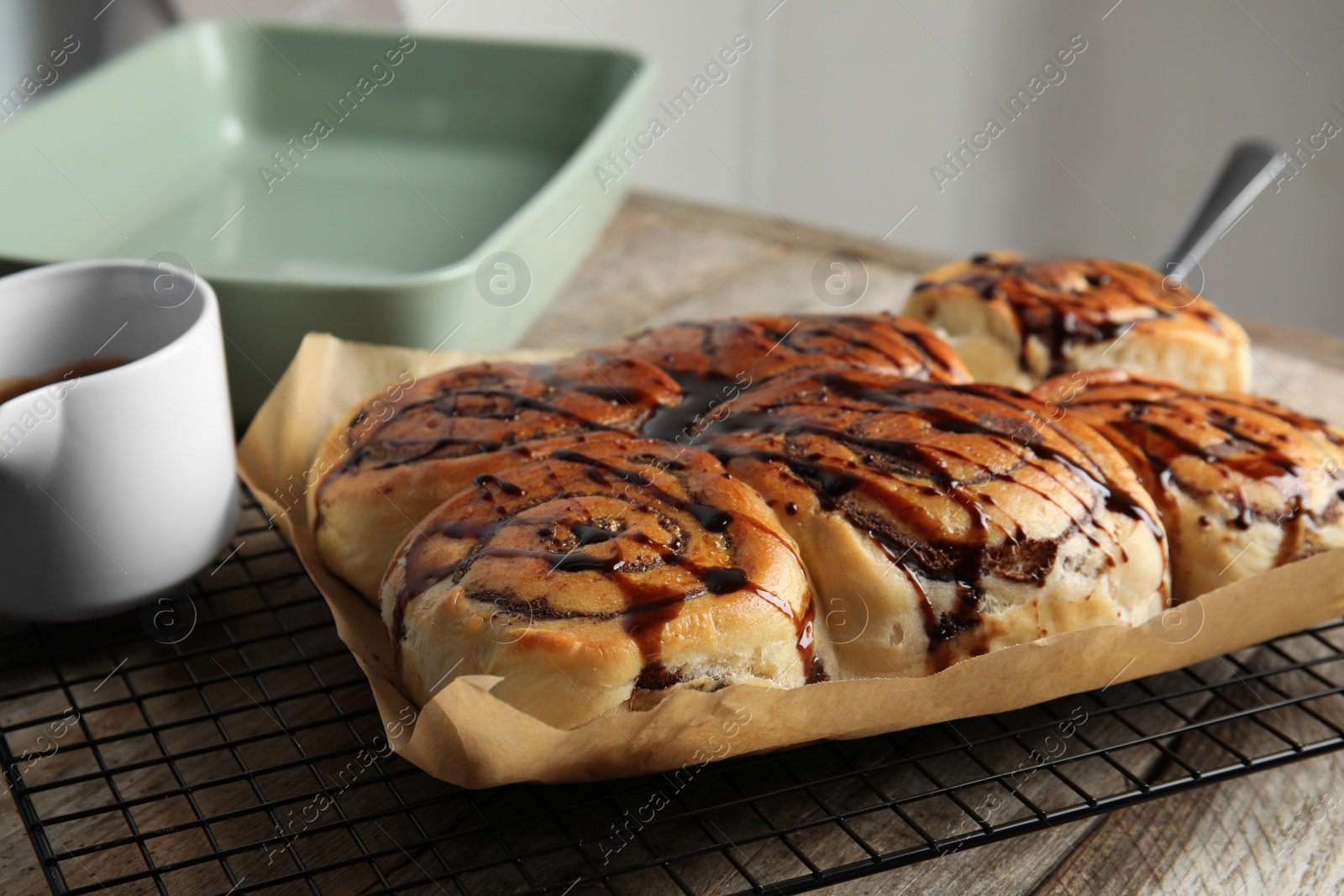 Photo of Cooling rack with freshly baked cinnamon rolls on table