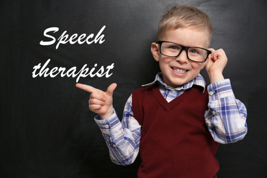 Cute little child near chalkboard and text Speech Therapist 