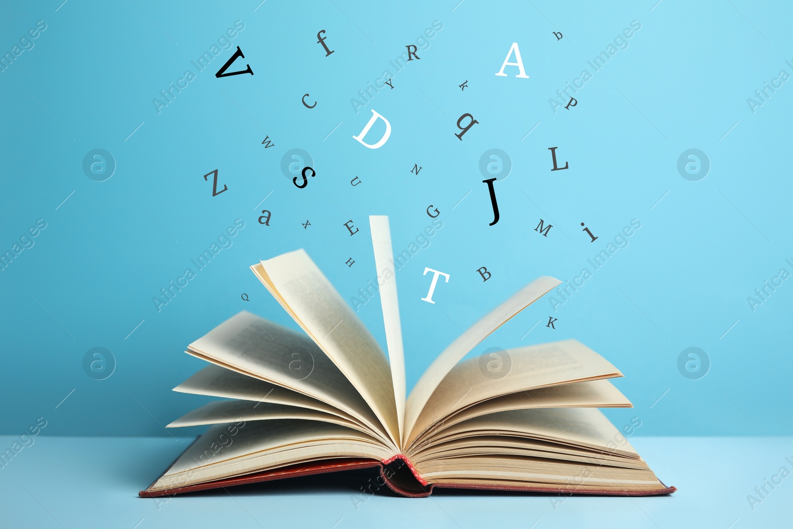 Image of Open book with letters flying out of it on light blue background