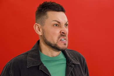 Photo of Angry man on red background. Hate concept