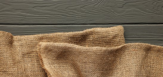 Burlap fabric on grey wooden table, top view