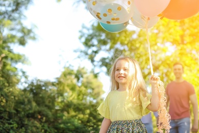 Photo of Cute little girl with colorful balloons outdoors on sunny day