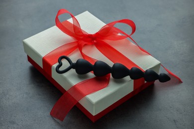 Photo of Black anal beads and gift box on grey table. Sex toy