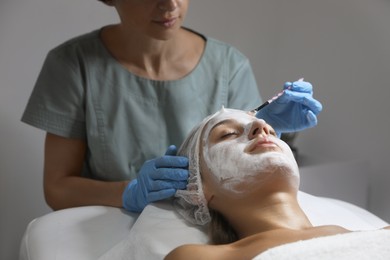 Photo of Cosmetologist applying mask on client's face in spa salon