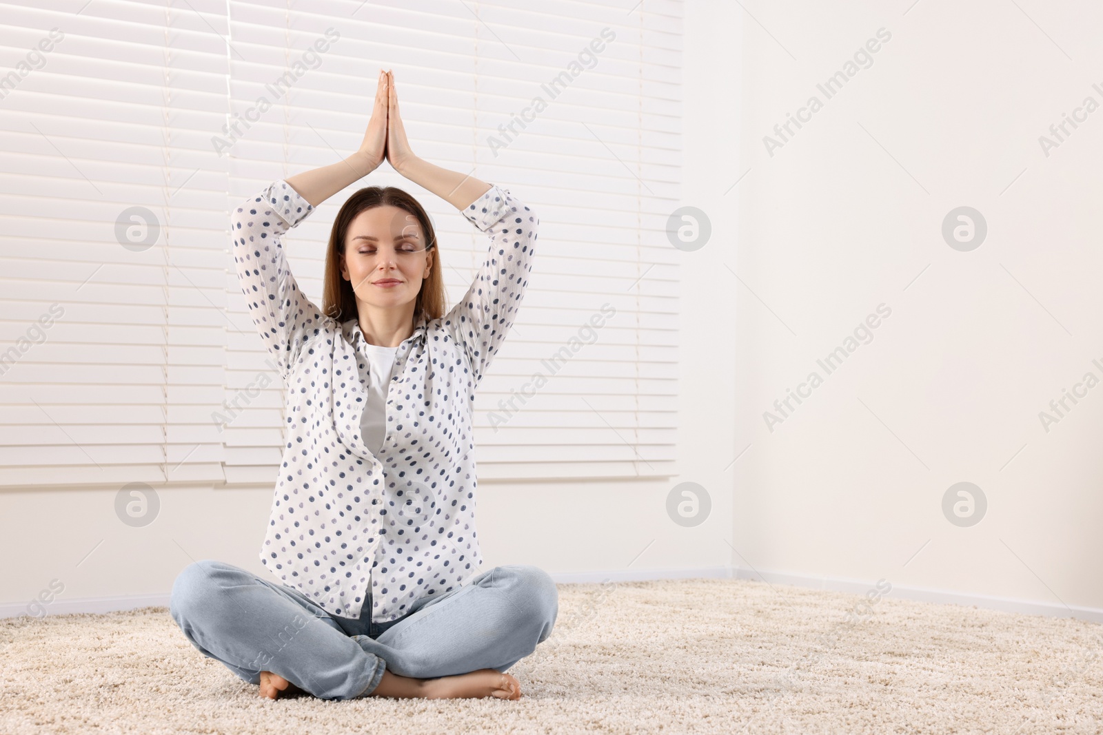 Photo of Woman meditating on carpet indoors, space for text