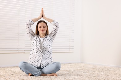 Woman meditating on carpet indoors, space for text