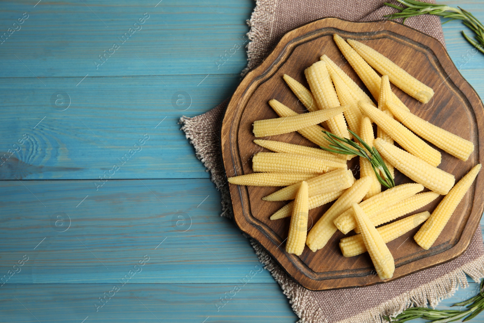 Photo of Fresh baby corn cobs on blue wooden table, flat lay. Space for text