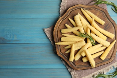 Fresh baby corn cobs on blue wooden table, flat lay. Space for text