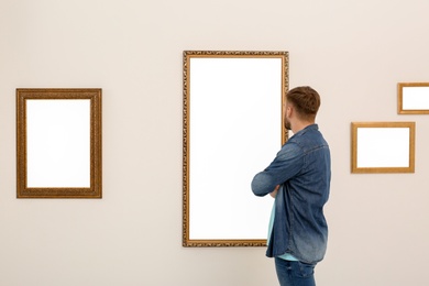 Young man viewing exposition in modern art gallery