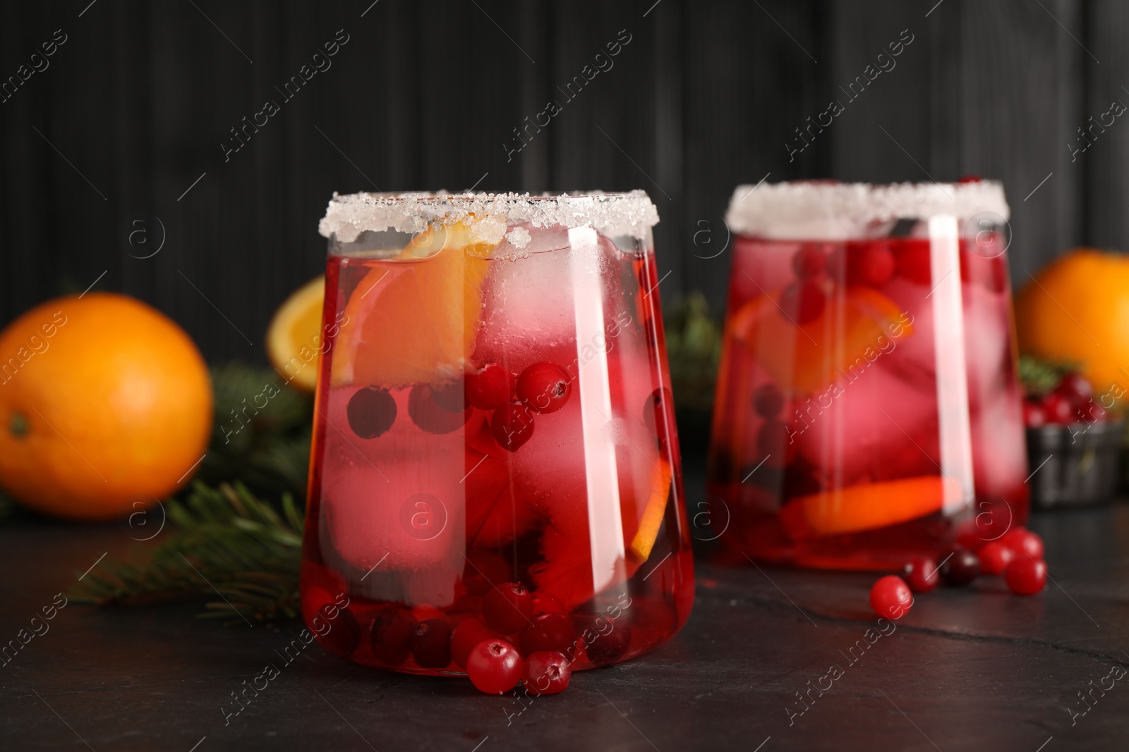 Photo of Tasty cranberry cocktail with ice cubes in glass on dark gray table