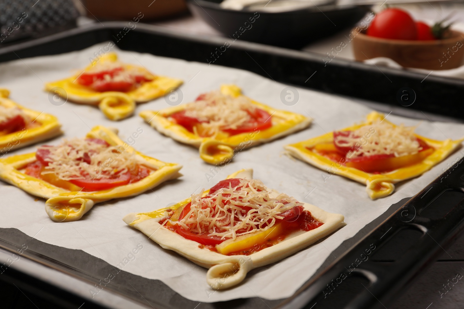 Photo of Baking sheet of raw puff pastry with tasty filling on table, closeup