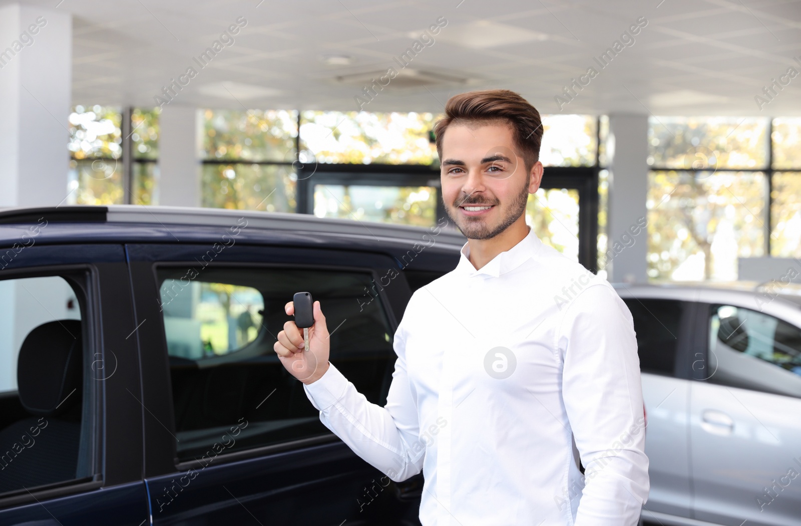 Photo of Young man with car key in dealership