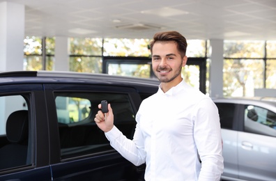 Photo of Young man with car key in dealership