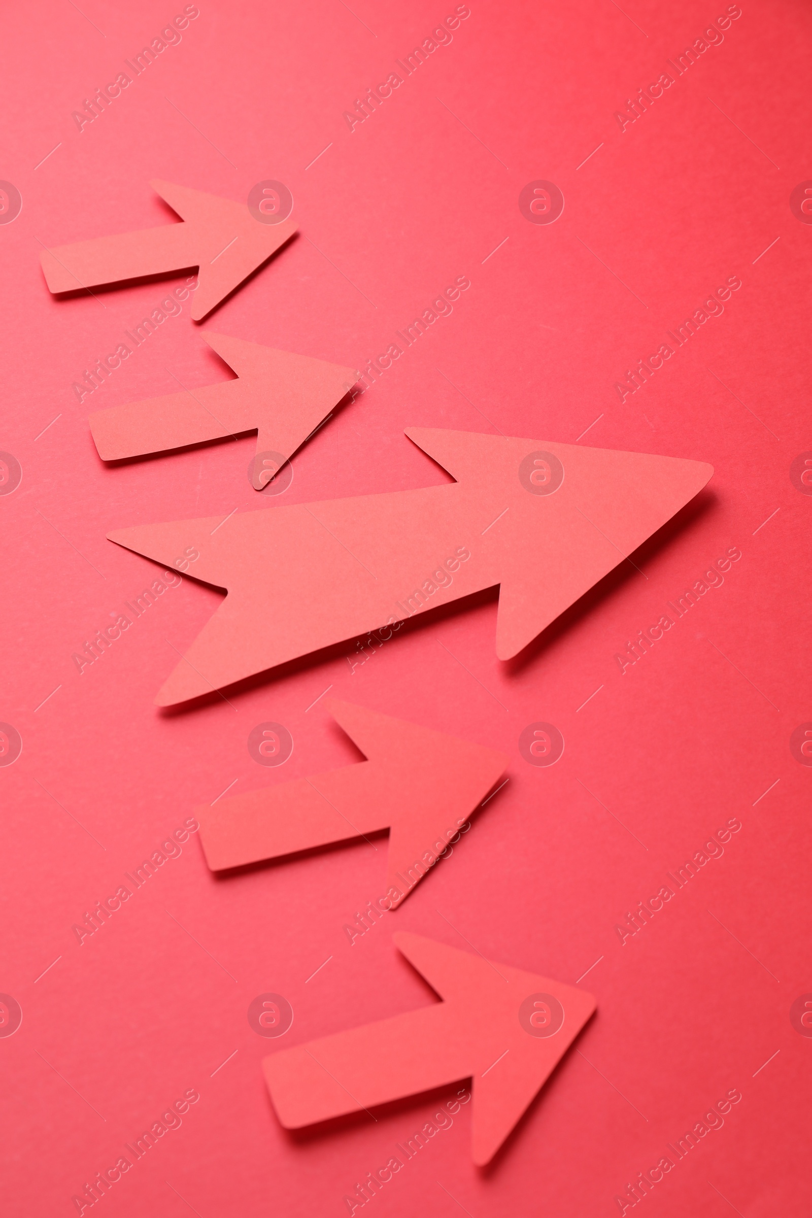 Photo of Many paper arrows on red background, above view