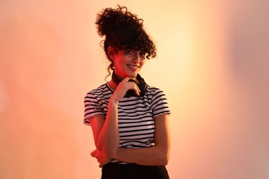 Photo of Beautiful young woman with headphones on color background in neon lights