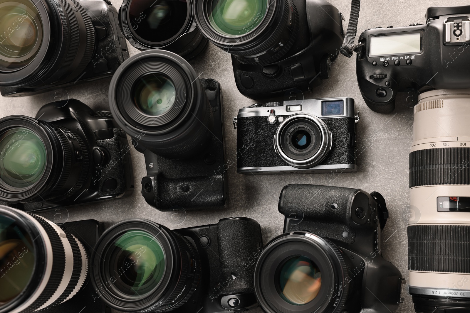 Photo of Modern cameras on gray textured table, flat lay