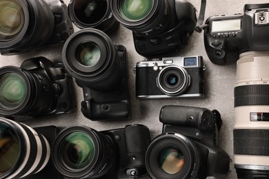 Photo of Modern cameras on gray textured table, flat lay