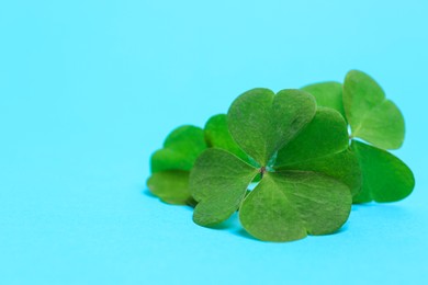 Photo of Beautiful green four leaves clover on light blue background, closeup. Space for text