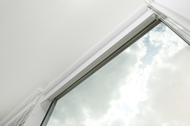 Photo of Modern window with white roller blinds indoors, low angle view