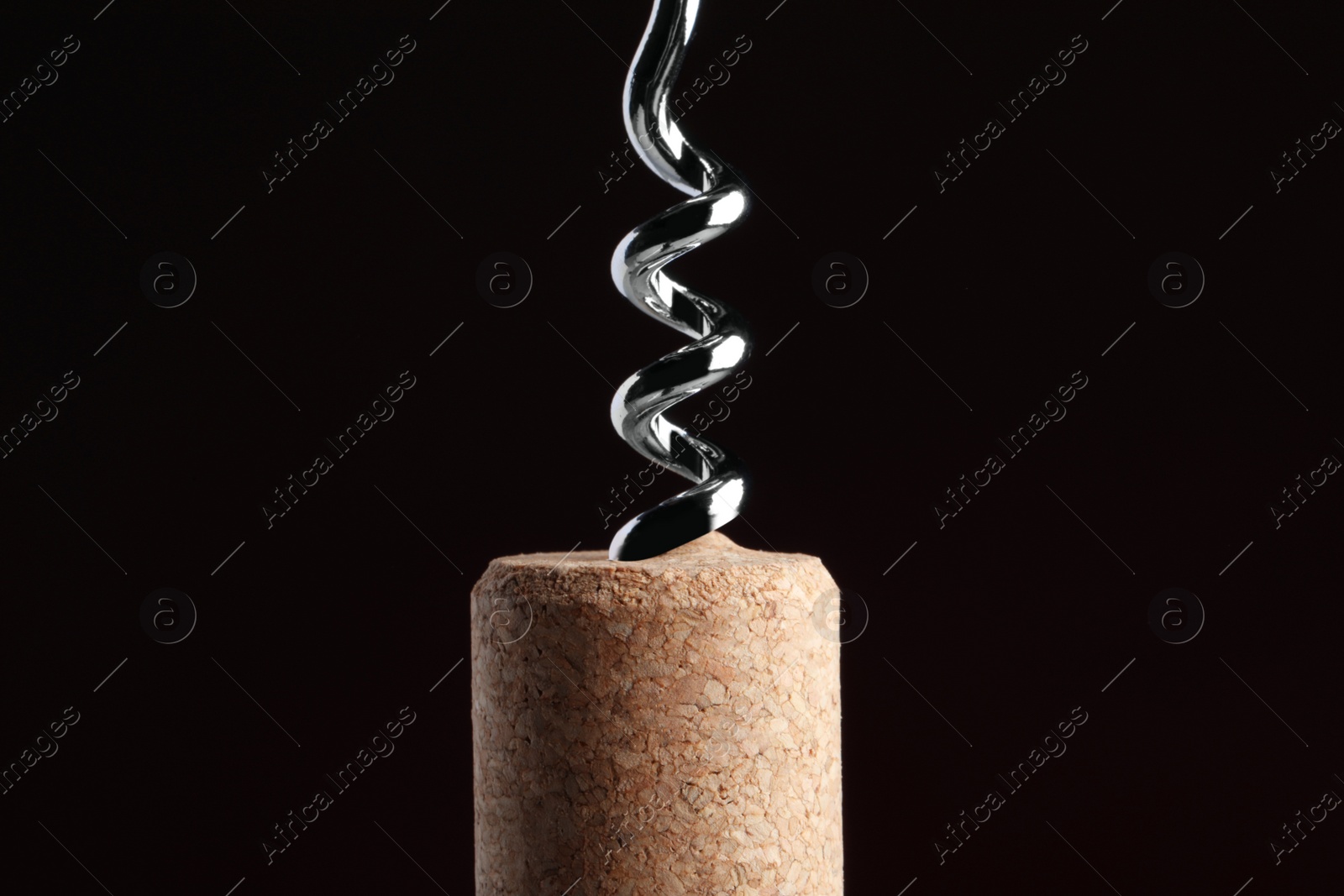 Photo of Corkscrew with cork against dark background, closeup