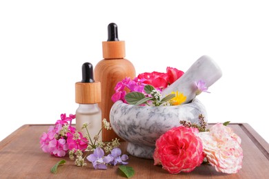 Photo of Bottles with essential oil and marble mortar with different flowers on wooden board against white background