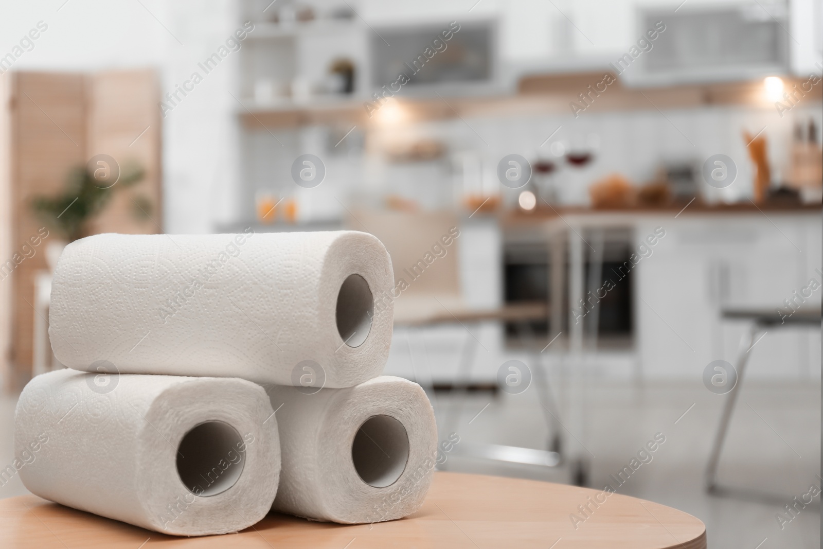 Photo of Rolls of paper towels on table in kitchen, space for text