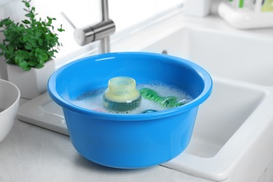 Photo of Light blue basin with baby bottles on white countertop in kitchen