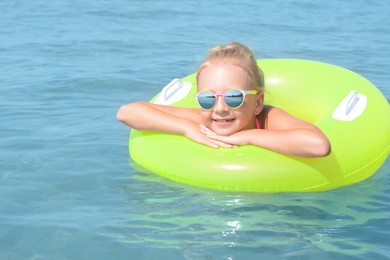 Happy little girl with inflatable ring in sea on sunny day
