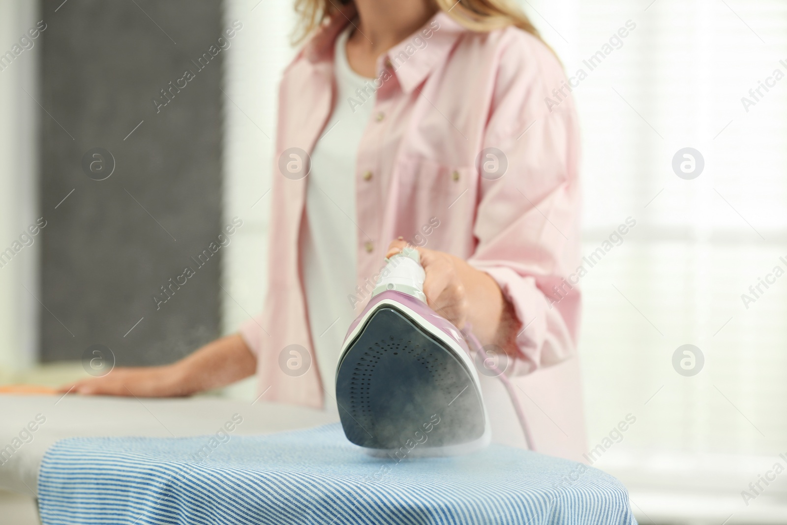 Photo of Girl ironing clean laundry at home, closeup