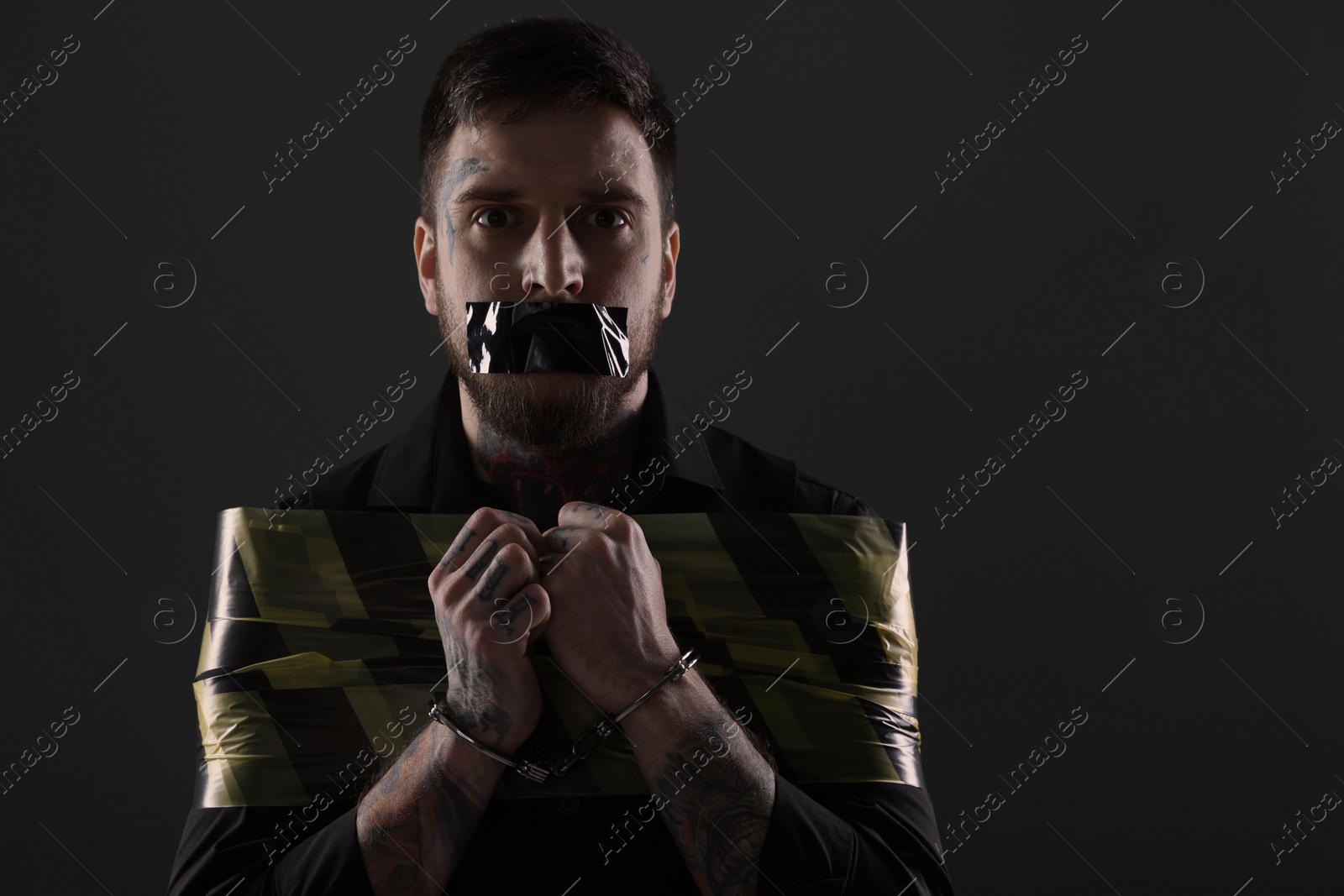 Photo of Man taped up and taken hostage on dark background. Space for text