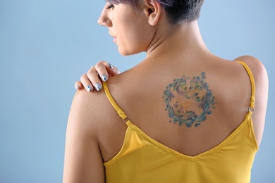 Photo of Young woman with tattoo on color background