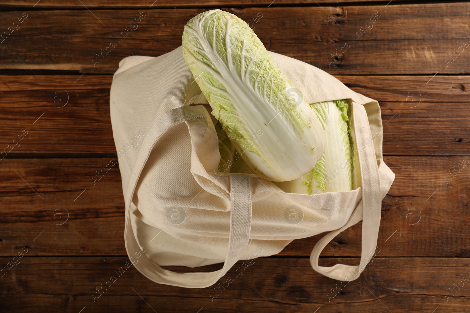 Photo of Textile eco bag with fresh ripe Chinese cabbages on wooden table, top view