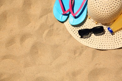 Photo of Straw hat, sunglasses, flip flops and refreshing drink on sand, flat lay with space for text. Beach accessories