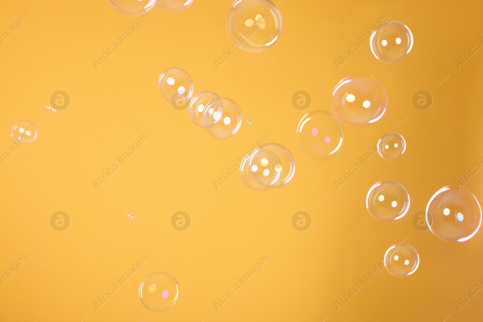 Photo of Many beautiful soap bubbles on orange background