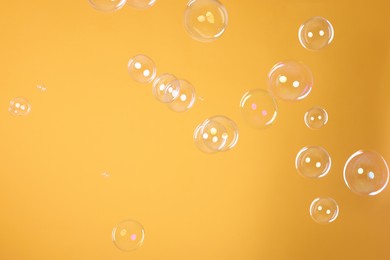 Many beautiful soap bubbles on orange background