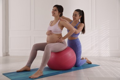 Trainer working with pregnant woman in gym. Preparation for child birth