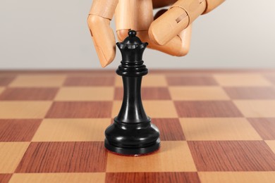 Photo of Robot with chess piece on board. Wooden hand representing artificial intelligence