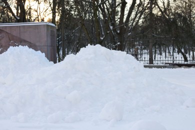 Photo of Piles of snow, trees and fence in winter park