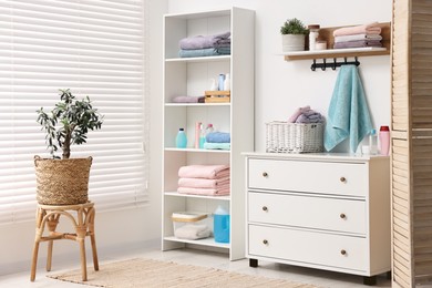 Photo of Fresh towels and toiletries on shelves indoors