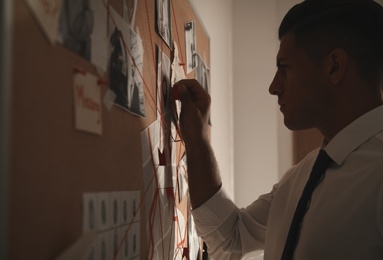 Detective looking at evidence board in office, closeup