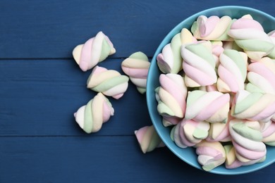 Bowl with colorful marshmallows on blue wooden table, flat lay. Space for text