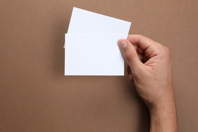 Photo of Man holding sheets of paper on brown background, closeup. Mockup for design